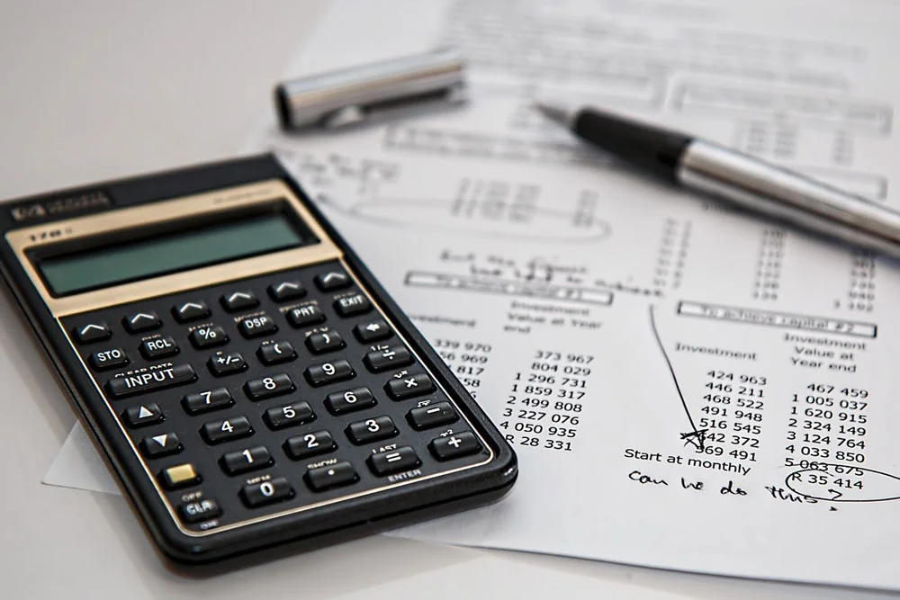 Papier avec une calculatrice et un stylo posés dessus